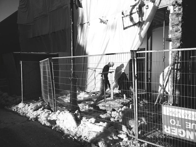 A black and white photograph showing a destroyed city street. Damaged buildings line the street, and there is rubble everywhere. It appears to be a warzone. No people are visible in the shot.