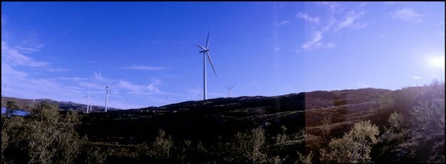 A split-screen image showing a wind turbine farm on one side, representing renewable energy, and a modern data center on the other, symbolizing digital trade and technology, with the flags of the US and EU subtly overlaid in the background.