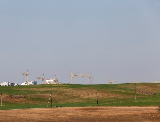 A medium shot of a wind farm in a rural, developing country. In the background, there are rolling hills and a clear blue sky. The image emphasizes sustainable development and renewable energy infrastructure.